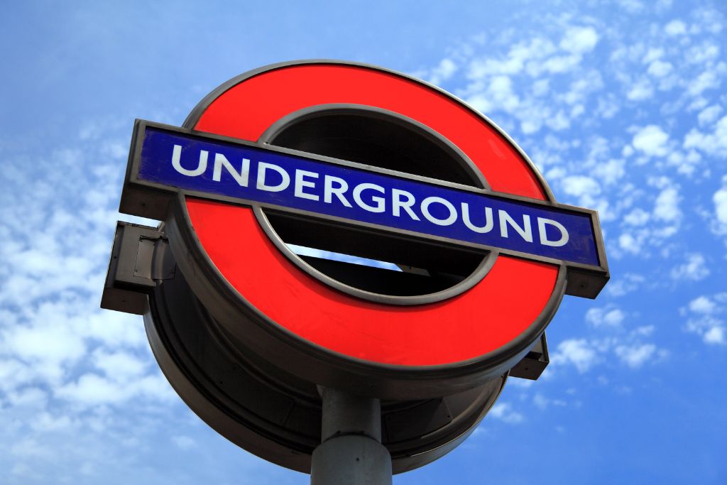 Iconic London Underground sign with a blue sky and white clouds in the background. 