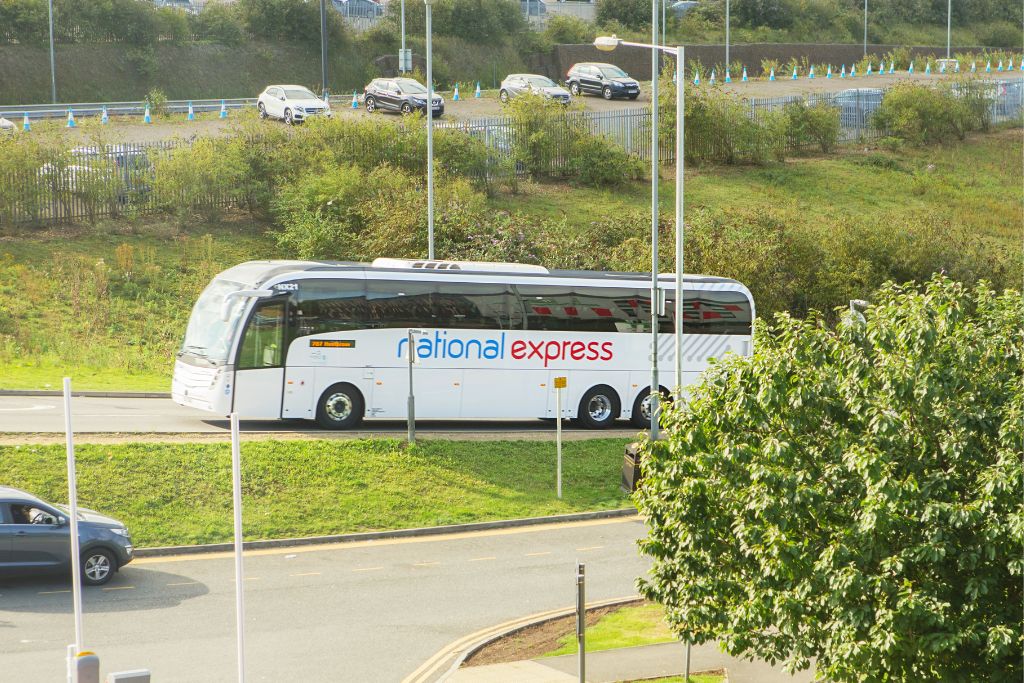 National Express coach on a paved road with green grass in the median and on the side of the road.