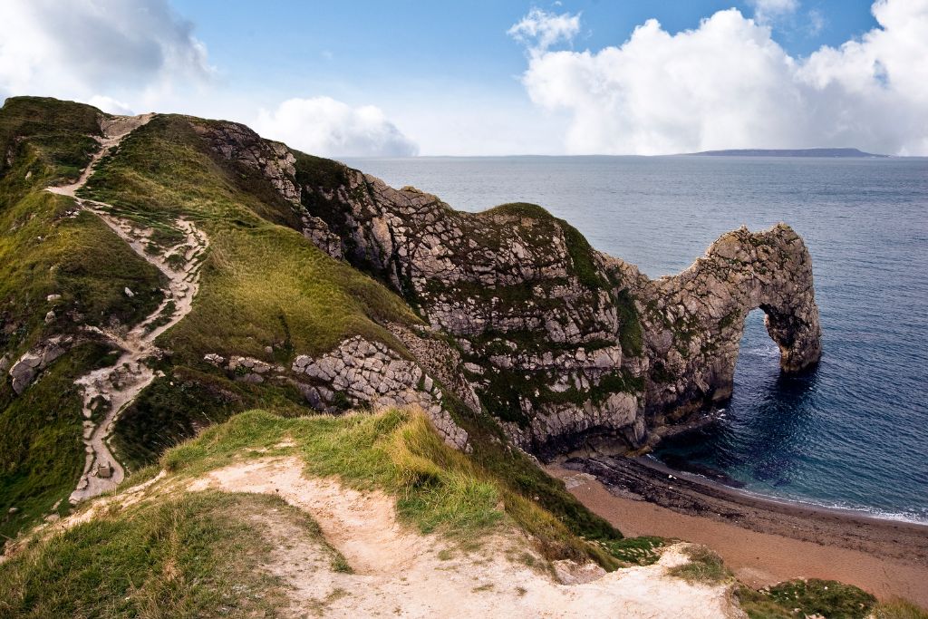 Narrow coastal path with green grass on each side. 
